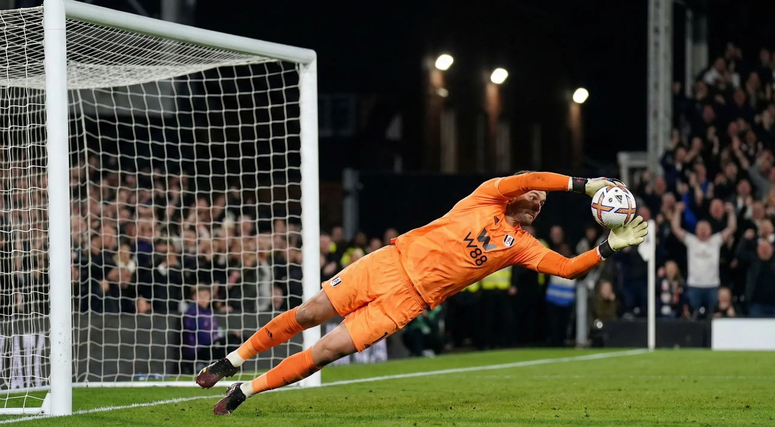 Goalkeeper making a diving save during a penalty shootout, dramatic action shot