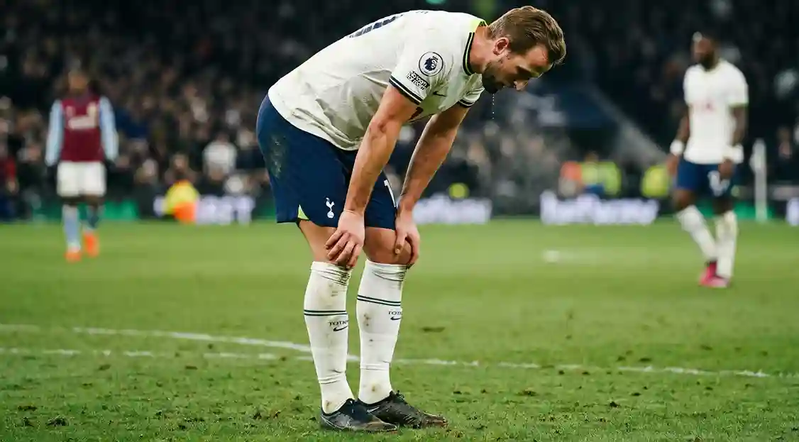 Football player showing signs of exhaustion during a match, bent over catching breath