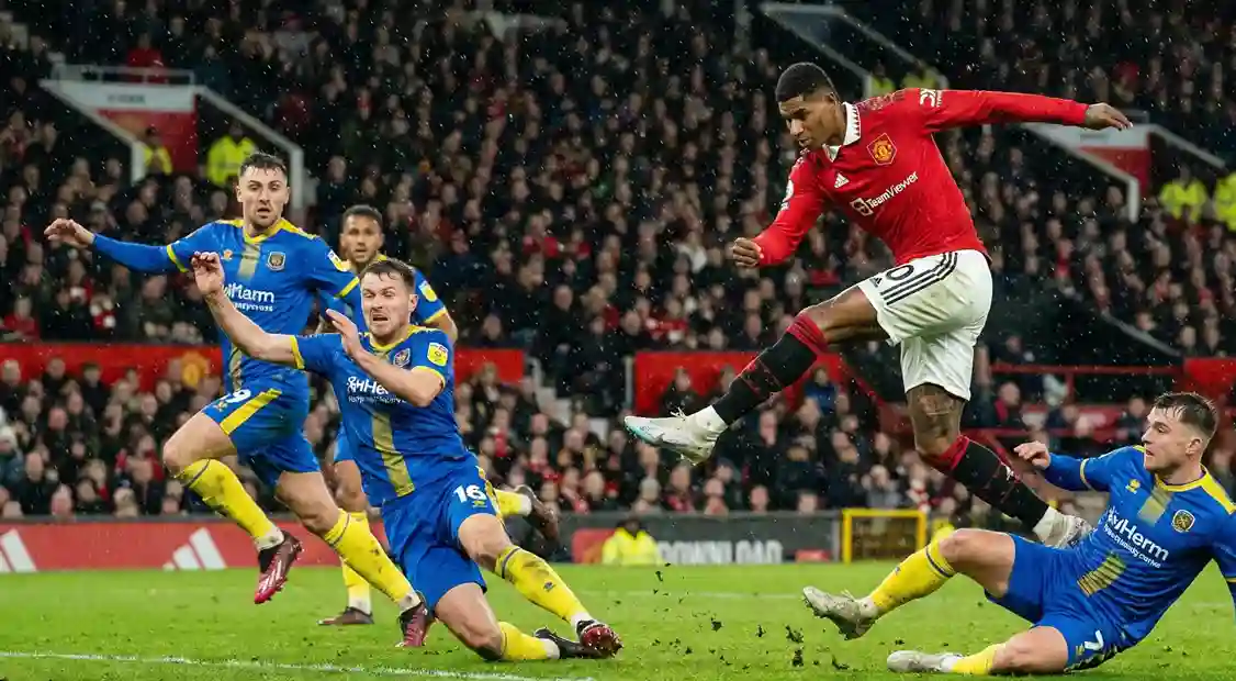 Premier League striker in action taking a shot at goal against lower league defenders