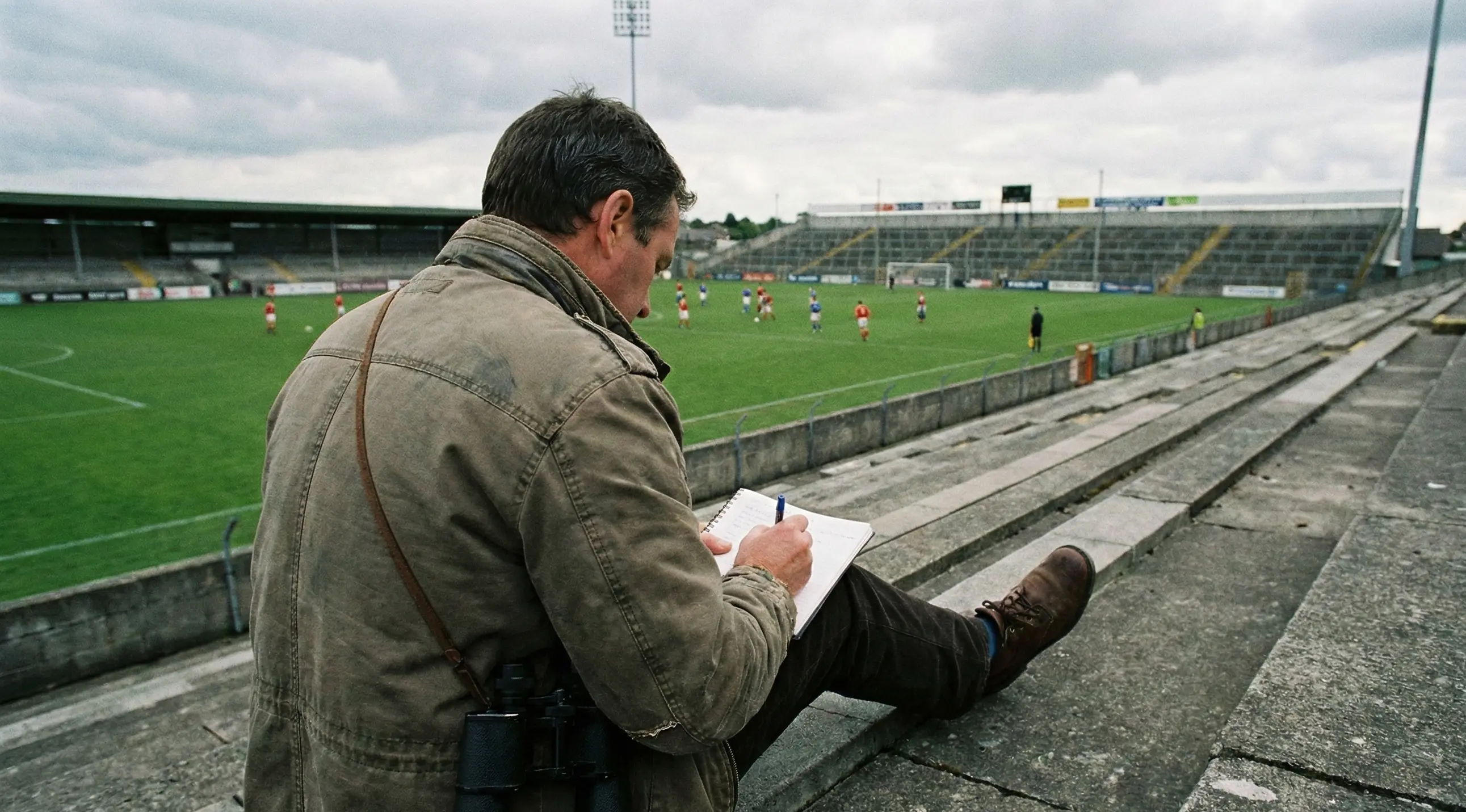 Football scout with notepad watching a youth team match from the stands